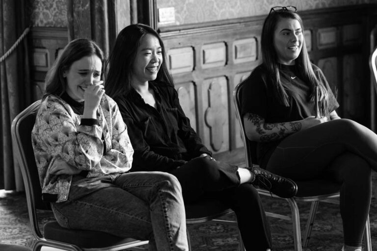 Black and white image of three professionals sitting in a learning and development seminar.