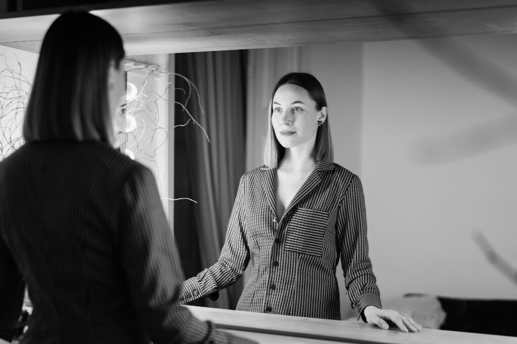 A business woman looks in the mirror as a means of self-reflection.