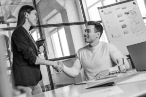 A new female hire shakes hands with a male colleague.