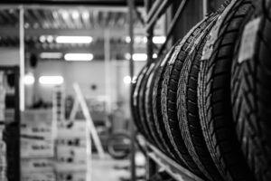 A range of tyres sit on a shelf in a busy car garage.